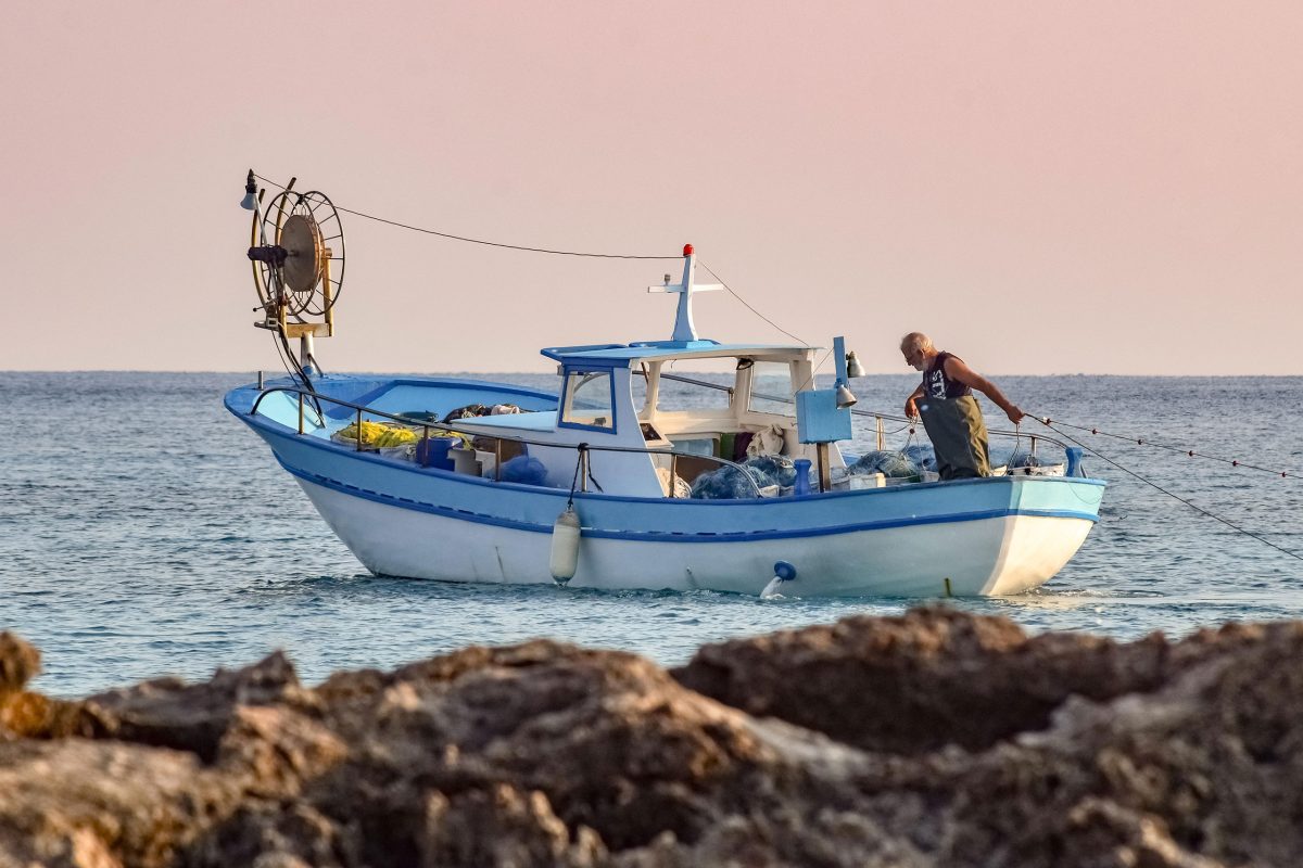 Petit bateau de pêche artisanale posant un filet au large, symbole de produits de la mer locaux et durables
