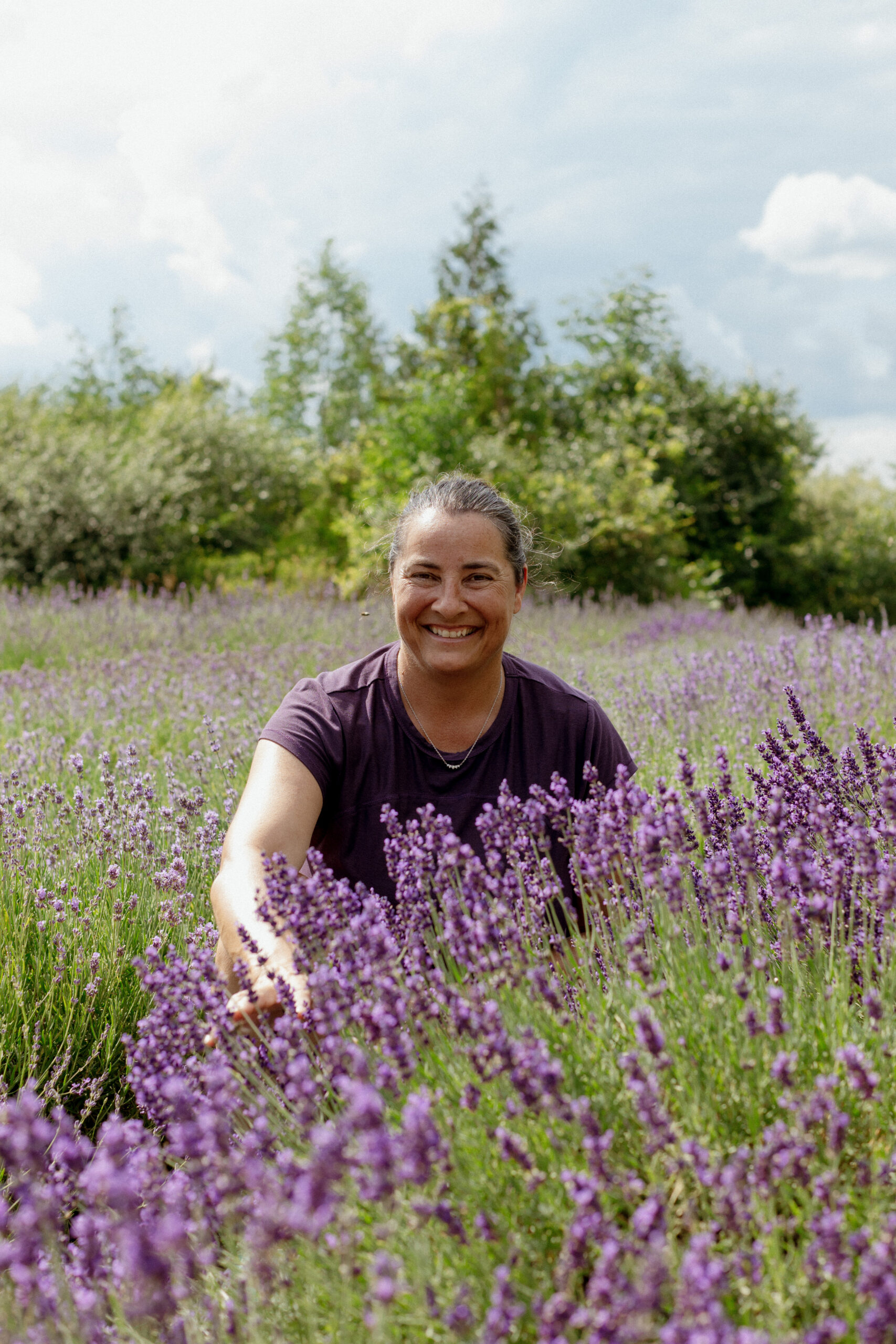 Monia, organic lavender grower at Lavenbel Farm, smiling in a blooming lavender field near Ottawa.